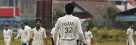 Cricketers in whites walking onto the field