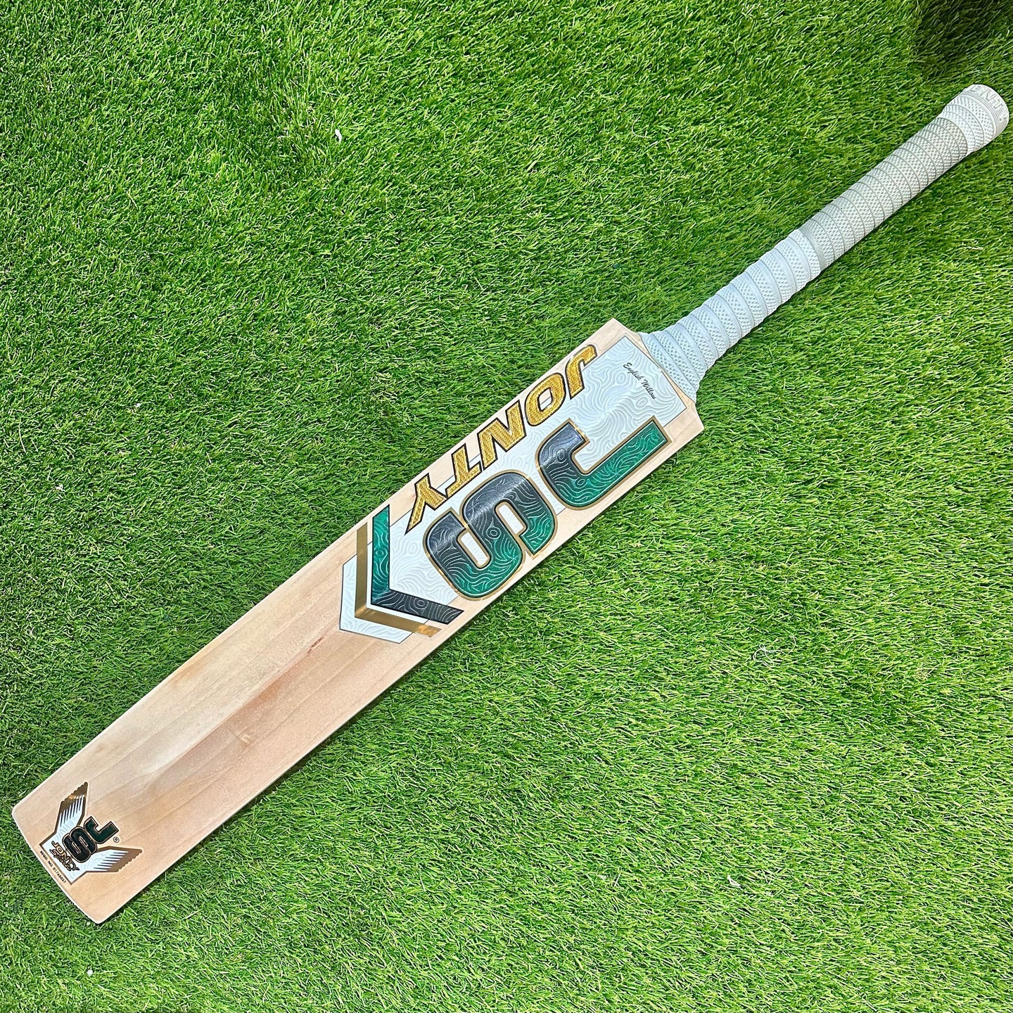Jonty Masters Grade-1 English Willow cricket bat with white handle grip on green grass background