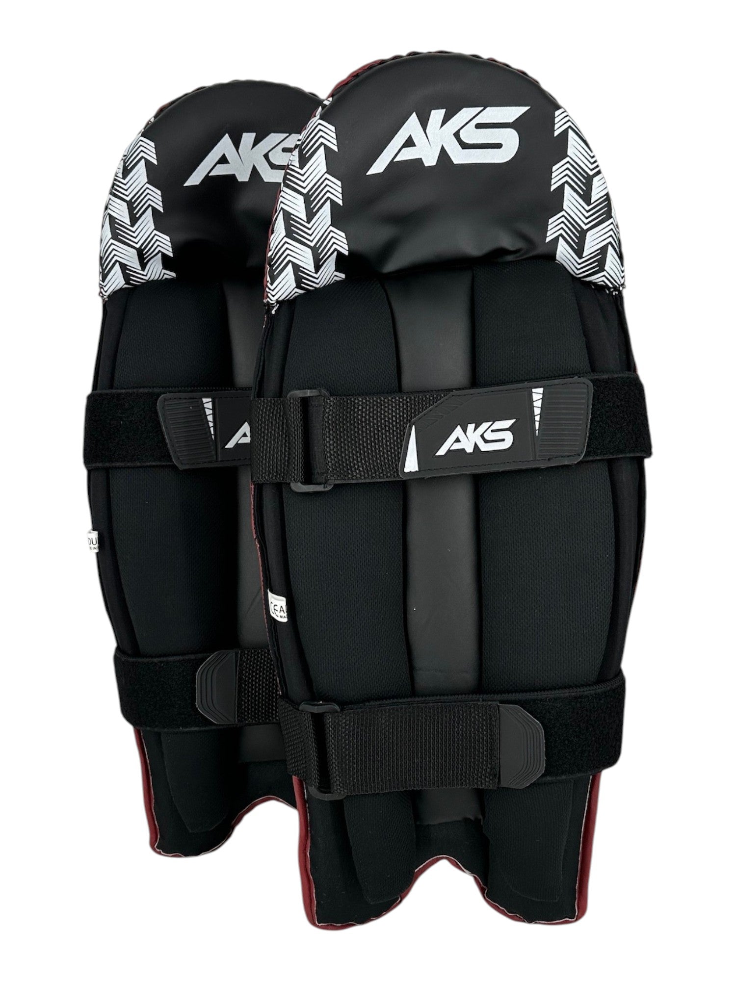 AKS CRICKET red and black wicket keeping pads with white chevron pattern, moulded knee roll, and adjustable straps.